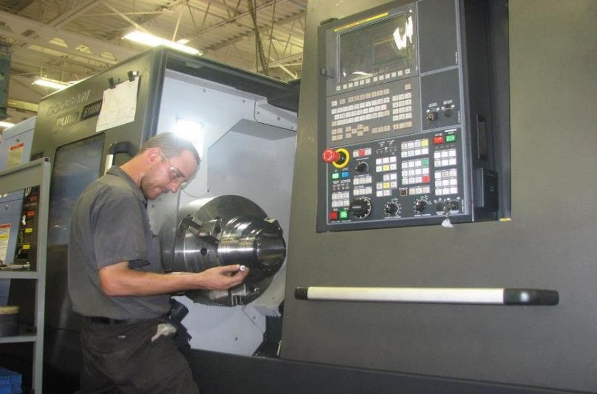 Man opening lathe machine and holding the chuck.